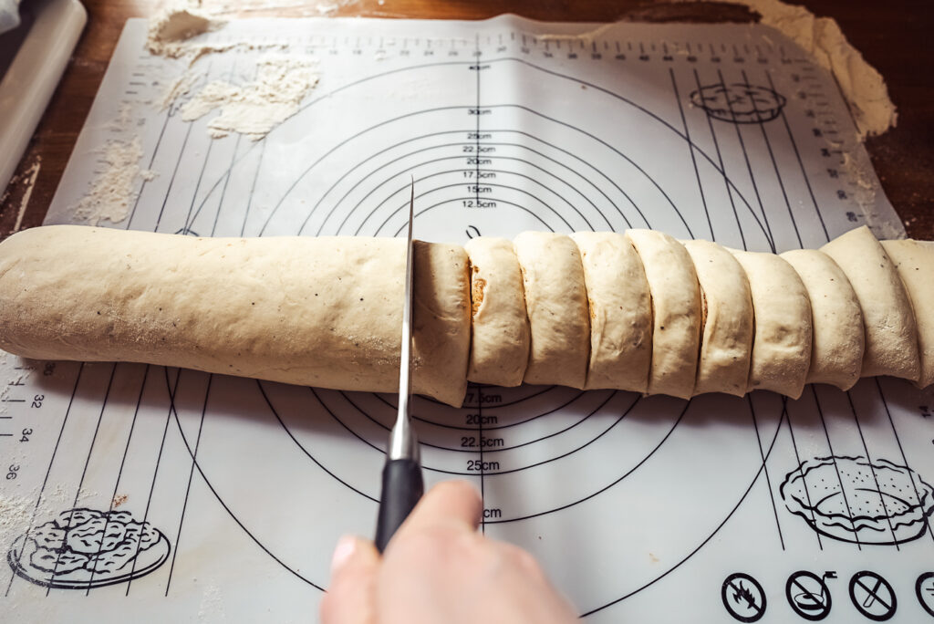 slicing cinnamon rolls for Norwegian kanelboller or solskinnsboller