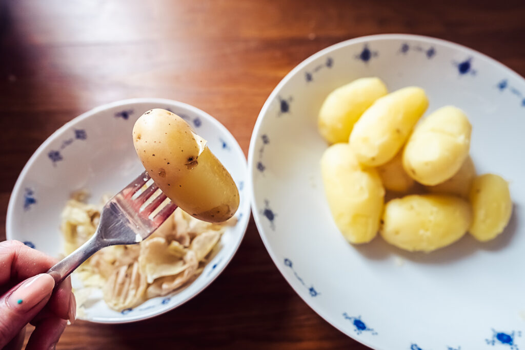peeling boiled potatoes for lomper