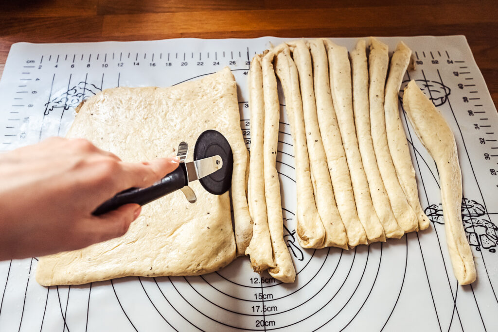 cutting cardamom bun dough into thin strips