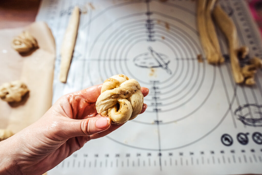 tying cardamom bun dough into a knot