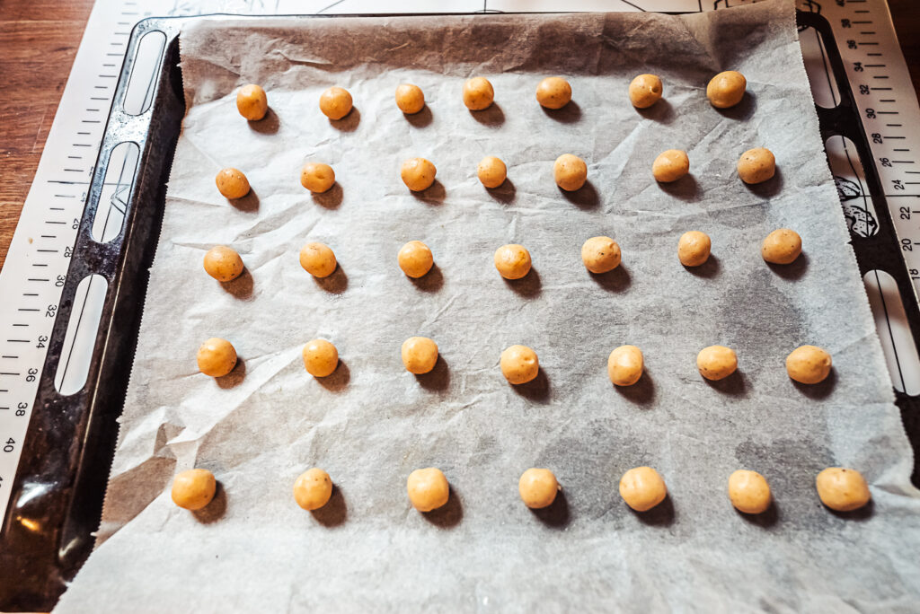 Pebernødder lined up on a baking sheet
