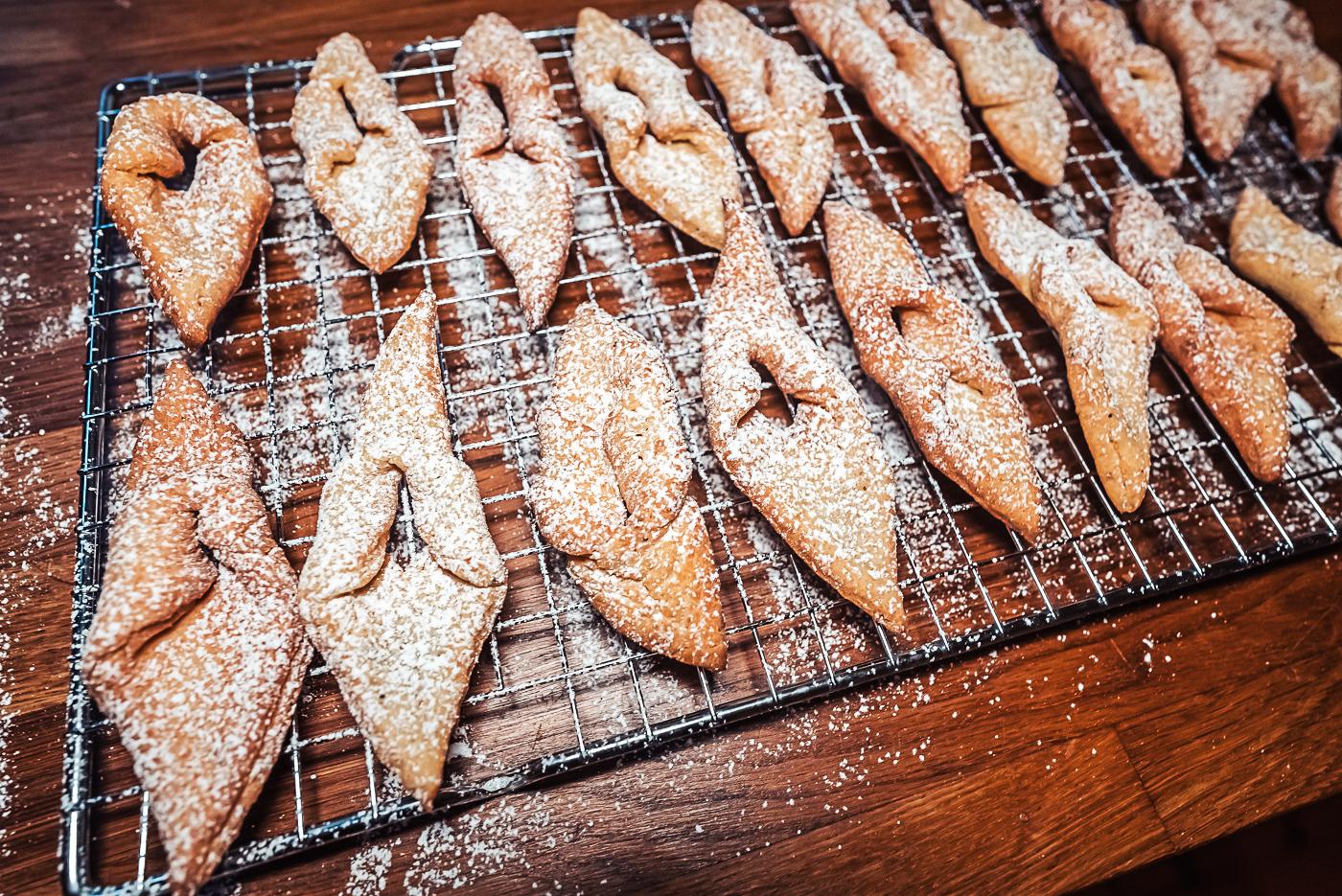 sprinkling fattigmann cookies with powdered sugar