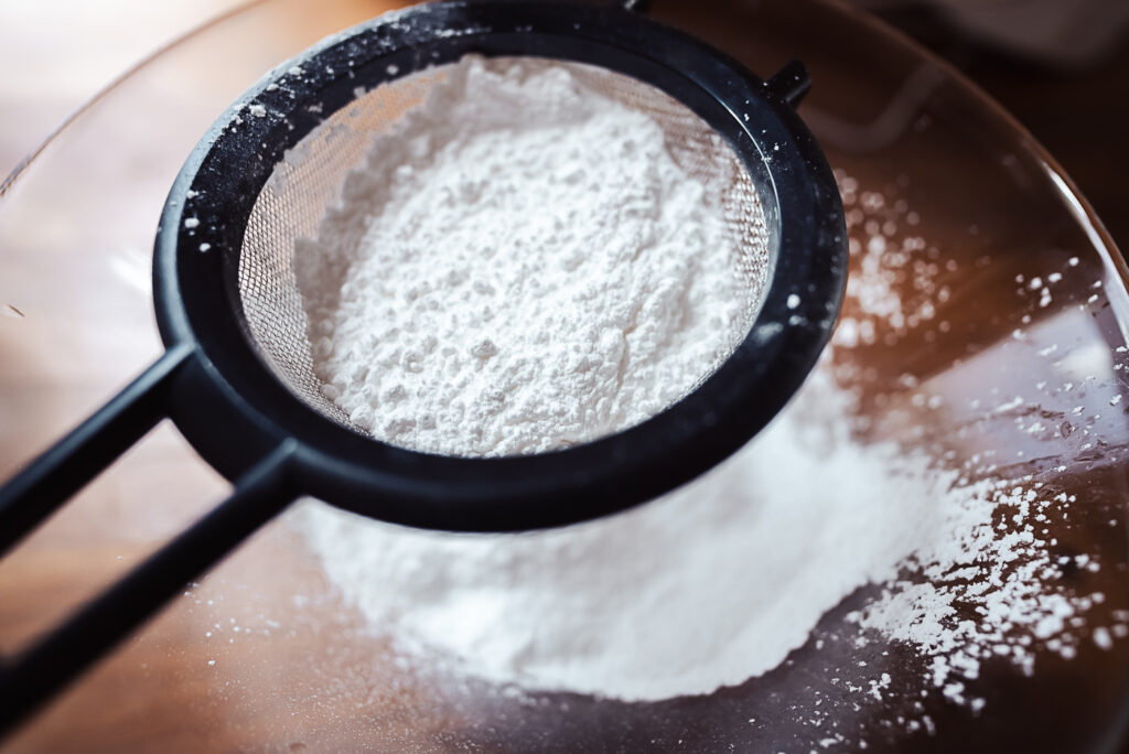 sifting powdered sugar into egg whites