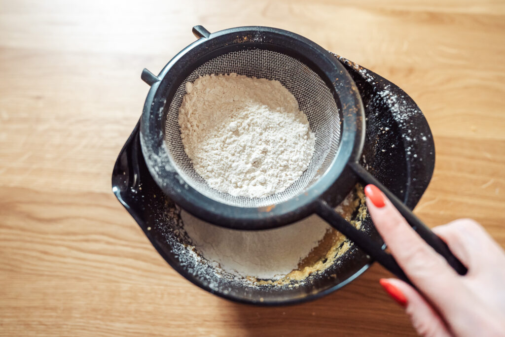 sifting flour into apple cake batter