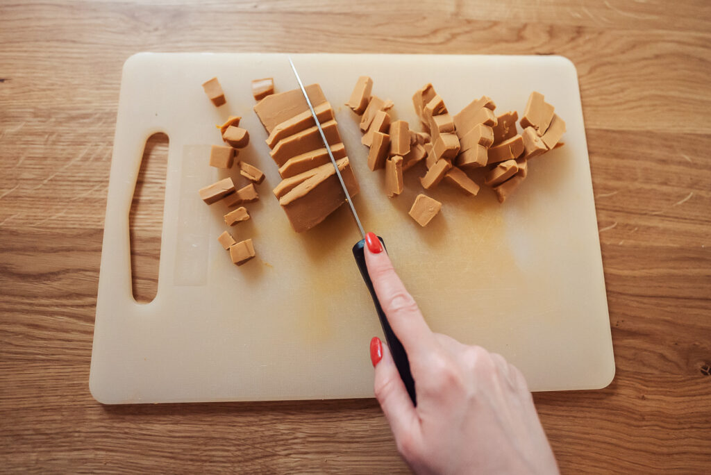 cutting Norwegian brown cheese into small pieces
