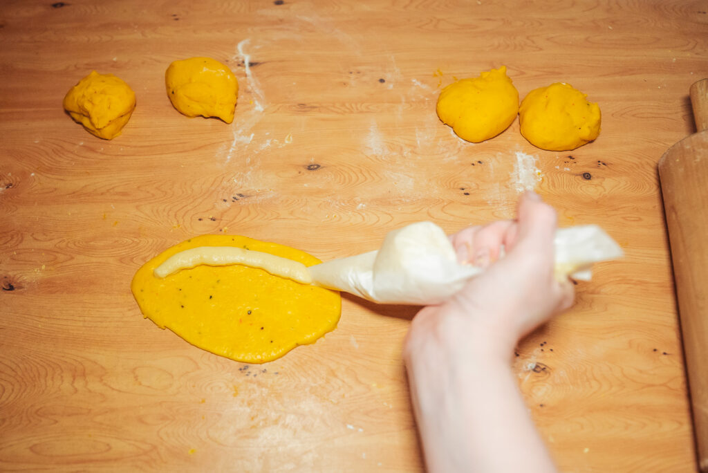 spreading vanilla filling across saffron bun dough