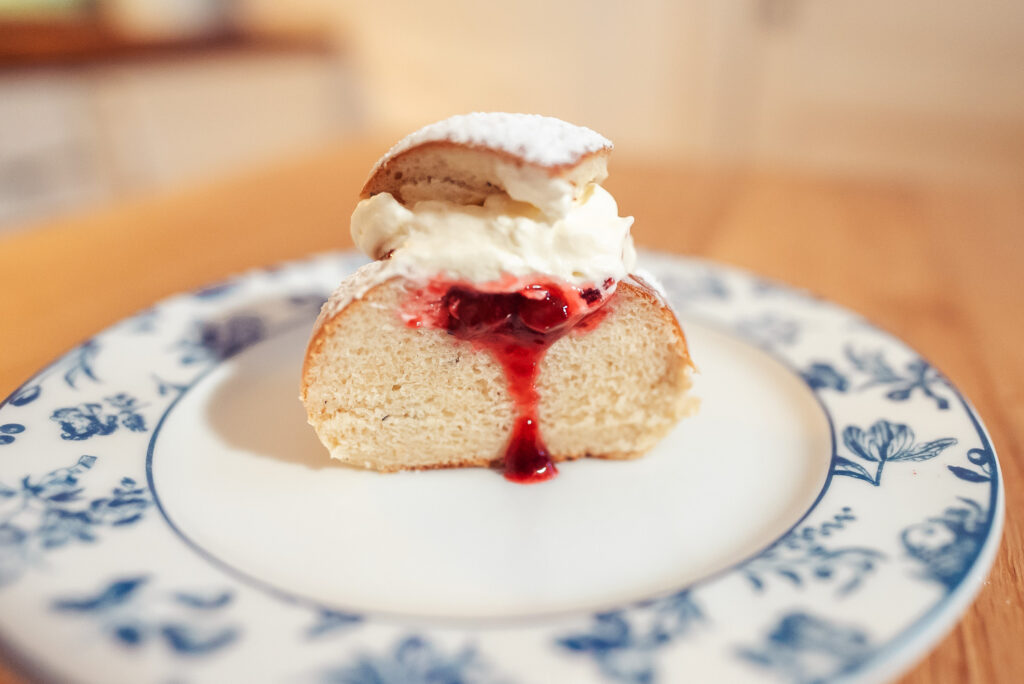 Norwegian fastelavnsboller with jam and whipped cream sliced in half on a plate