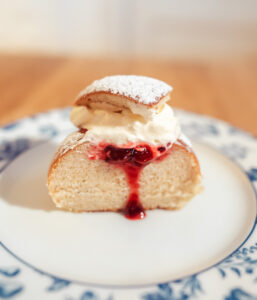 Norwegian fastelavnsboller with jam and whipped cream sliced in half on a plate