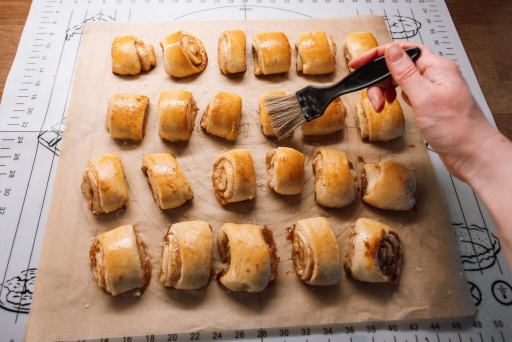 brushing Swedish gifflar cinnamon rolls with syrup