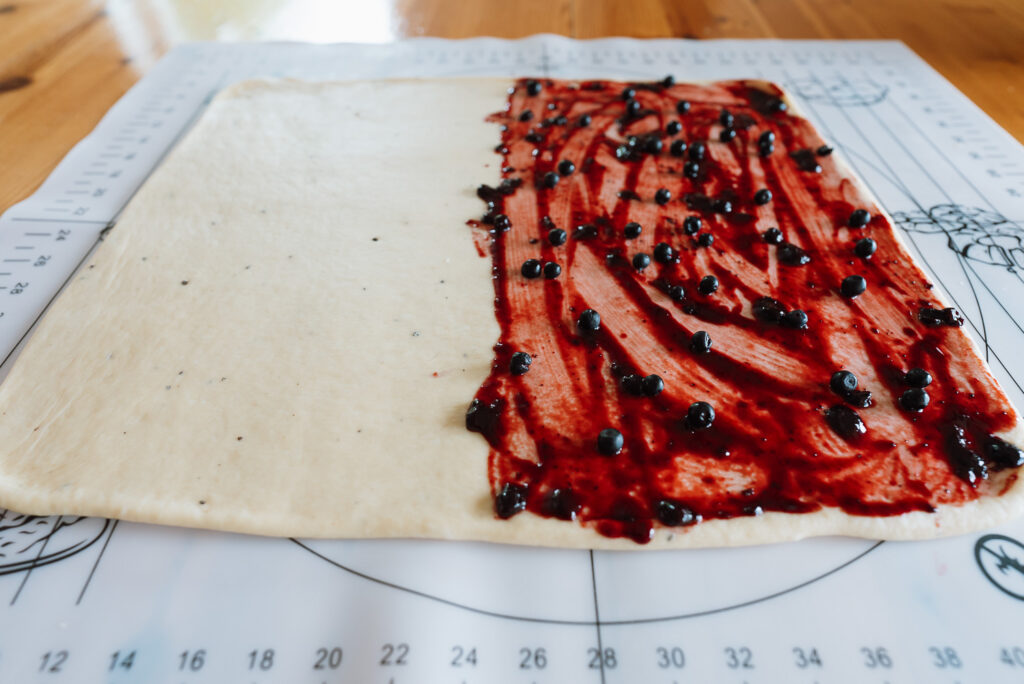 rolling out dough with blueberry jam to make blueberry buns