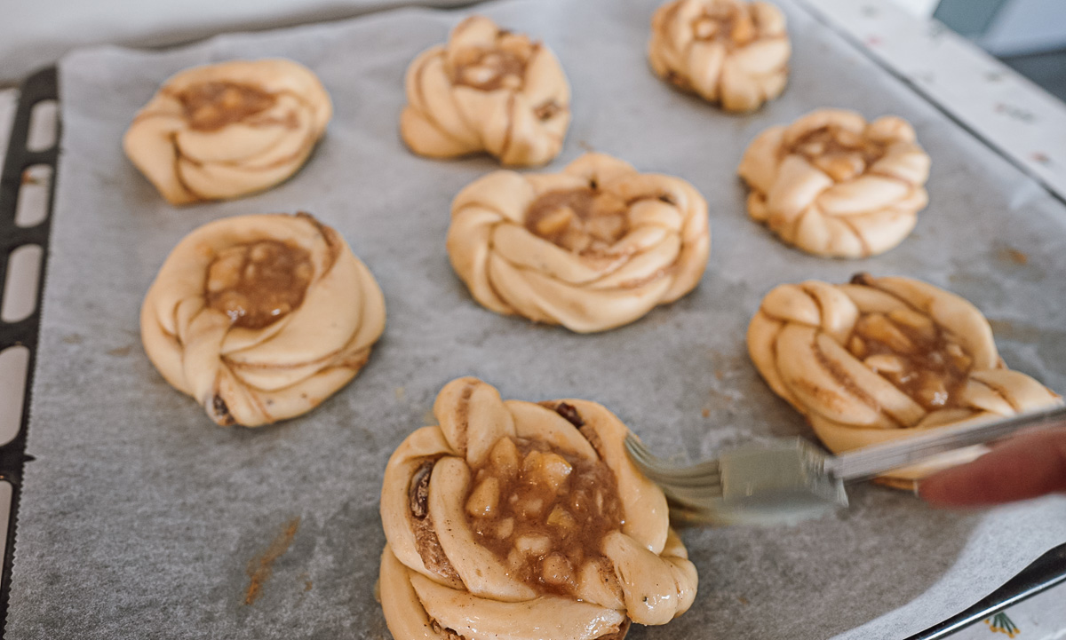 brushing apple cinnamon buns with egg wash